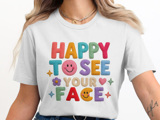 White t-shirt with colorful felt letters that read "HAPPY TO SEE YOUR FACE".