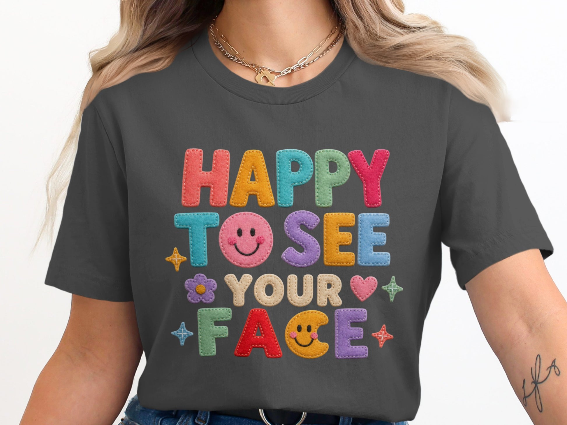 Dark grey t-shirt with colorful felt letters reading "HAPPY TO SEE YOUR FACE."