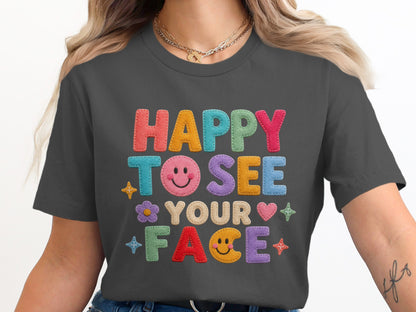 Dark grey t-shirt with colorful felt letters reading "HAPPY TO SEE YOUR FACE."