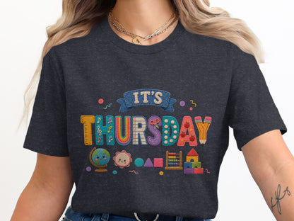 Dark t-shirt with colorful "IT'S THURSDAY" text and school-themed graphics.