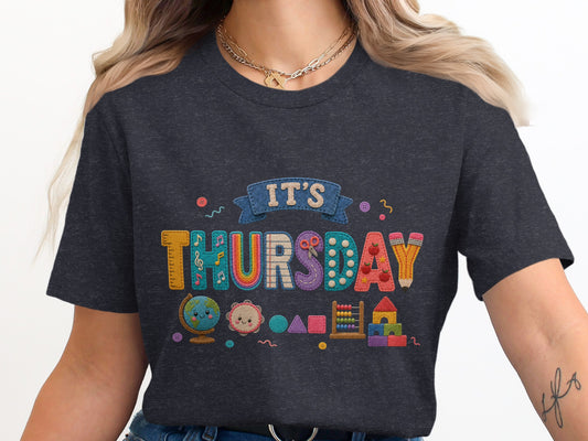 Dark t-shirt with colorful "IT'S THURSDAY" text and school-themed graphics.