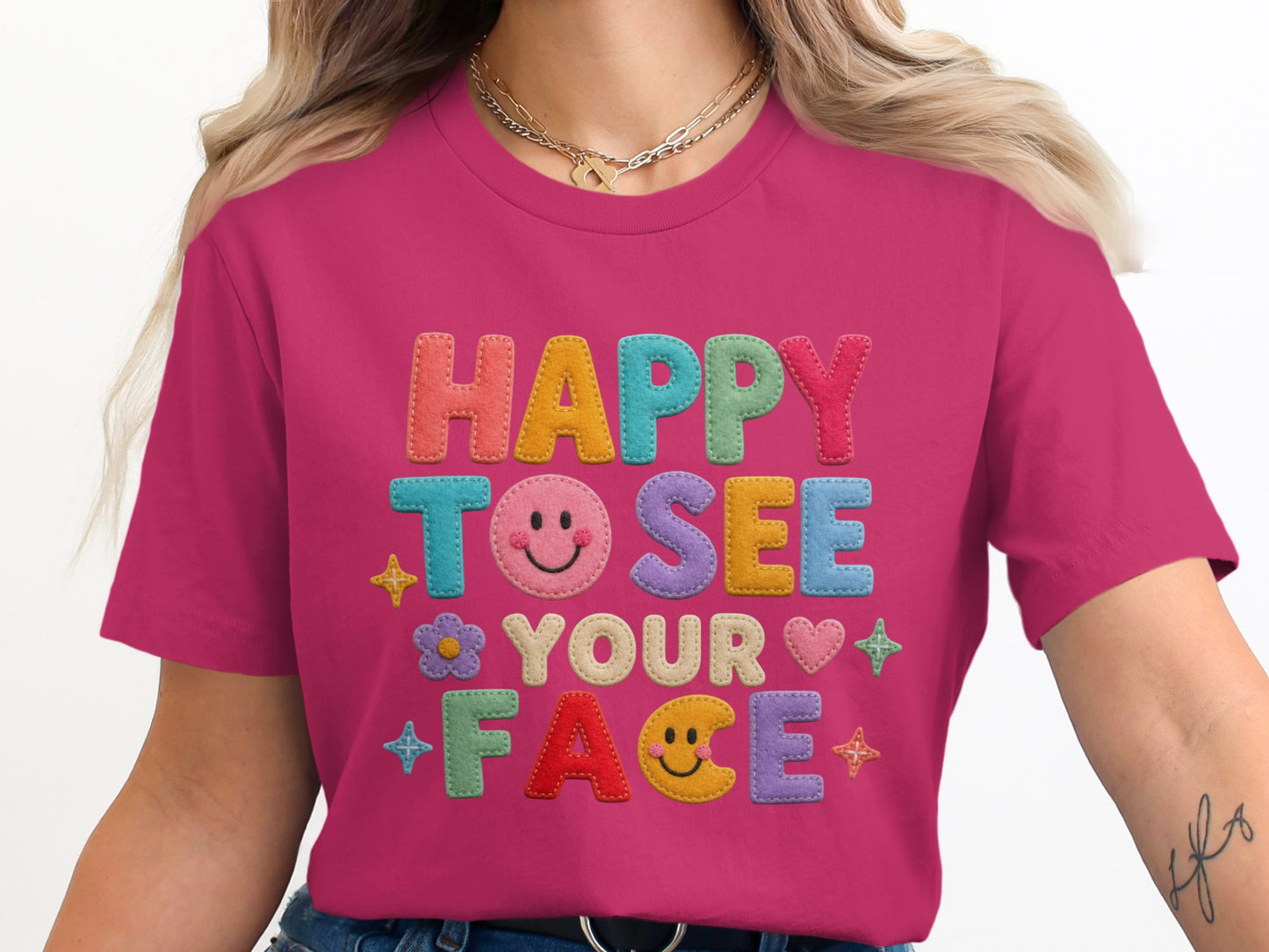 Pink t-shirt with "HAPPY TO SEE YOUR FACE" in colorful felt letters and icons.