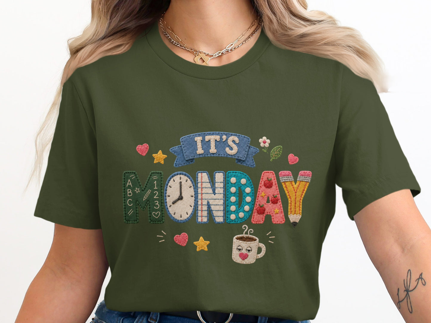 Green t-shirt with "IT'S MONDAY" embroidered with school-themed icons.