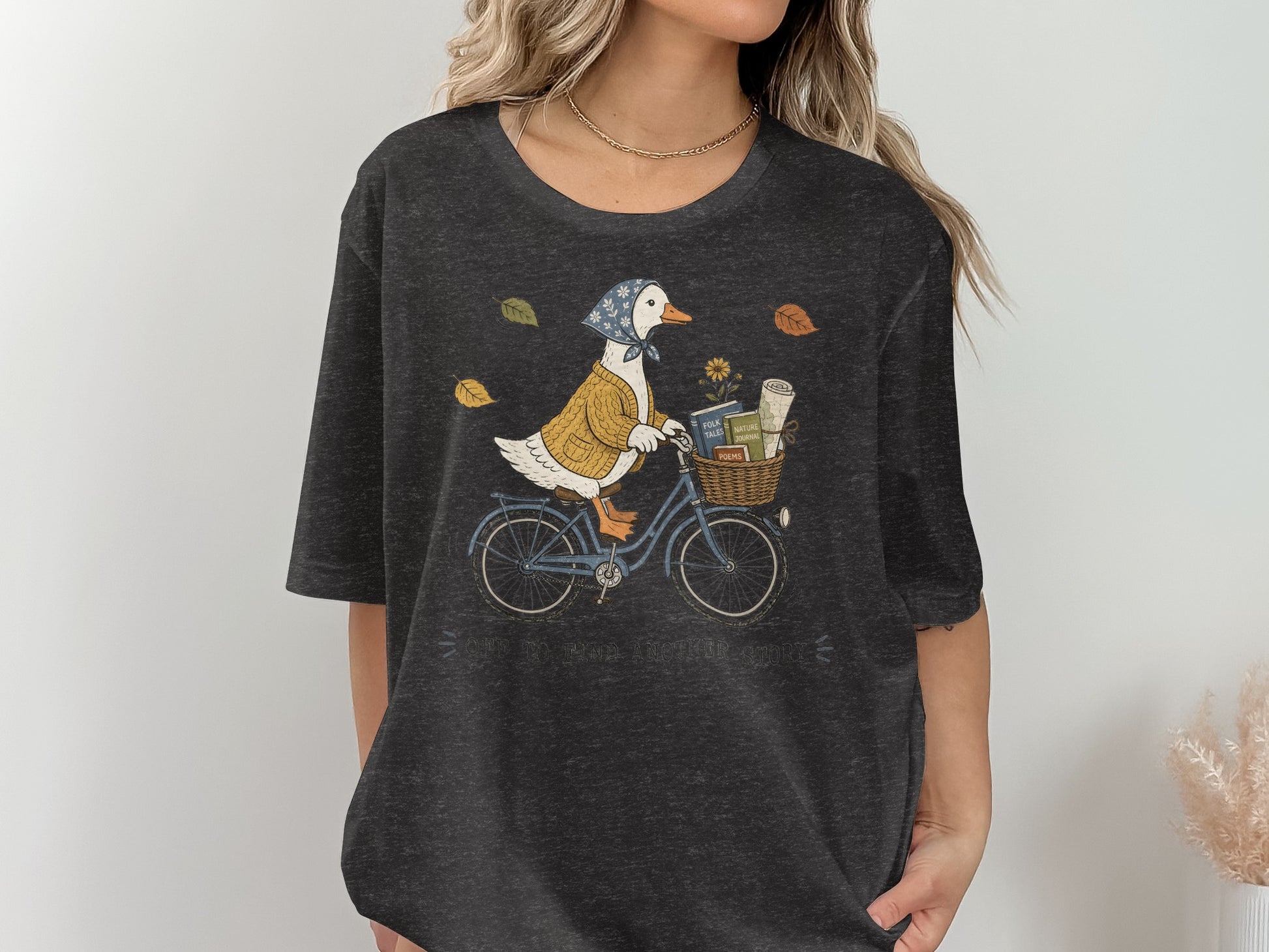 Duck on a bicycle with a basket of books, text reads "OFF TO FIND ANOTHER STORY."
