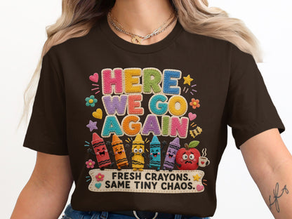 Brown t-shirt with "HERE WE GO AGAIN" and funny crayons and apple graphic.