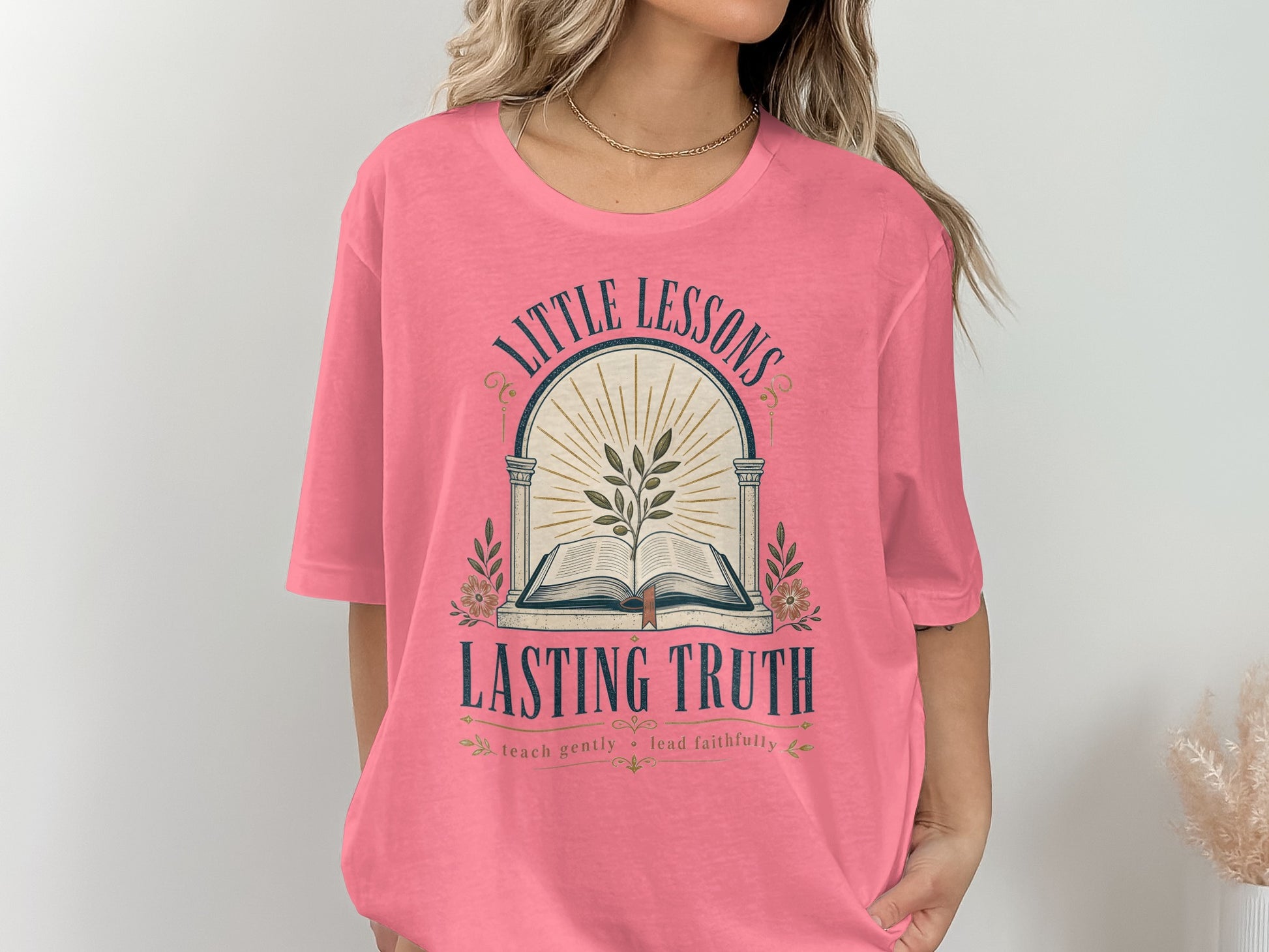 Pink t-shirt with "Little Lessons Lasting Truth" text and an open book design.