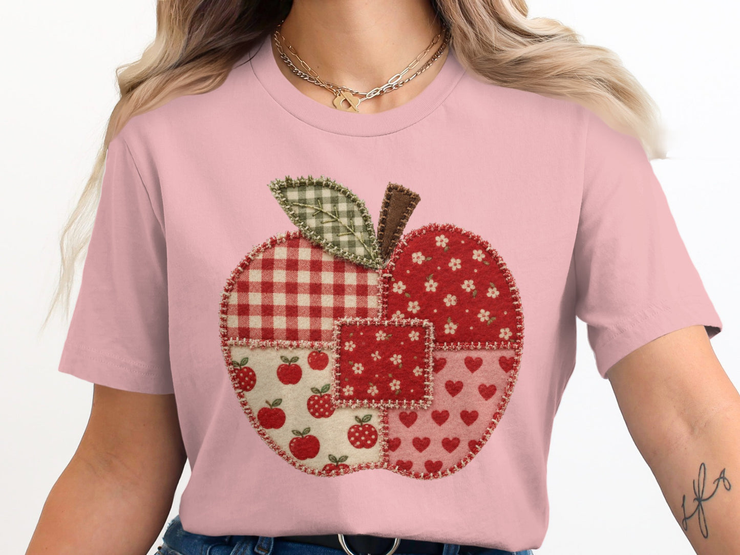 Pink t-shirt with a patchwork apple graphic including gingham, floral, apple, and heart patterns.