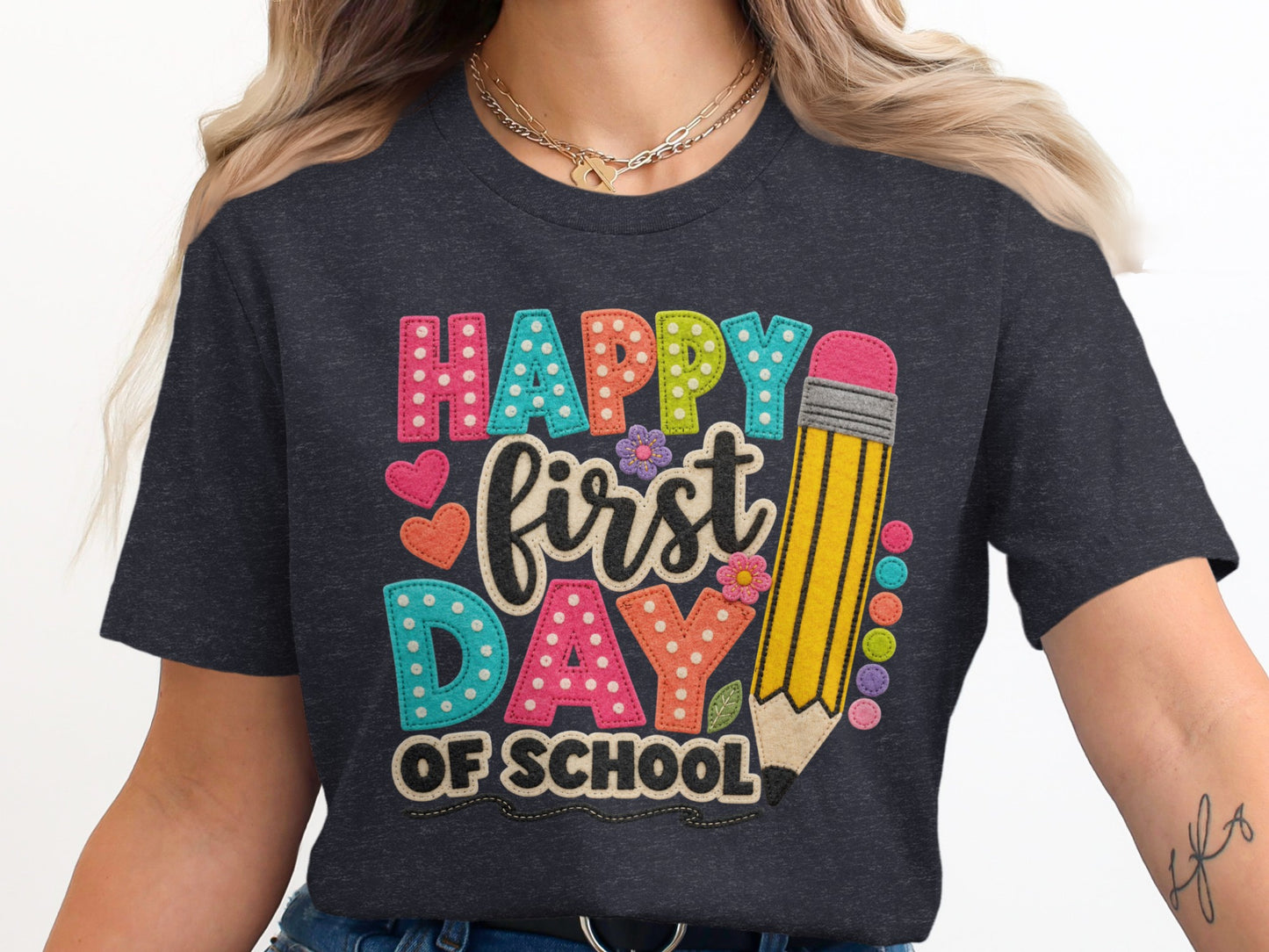 "Happy First Day of School" text with pencil and decorative elements on t-shirt.