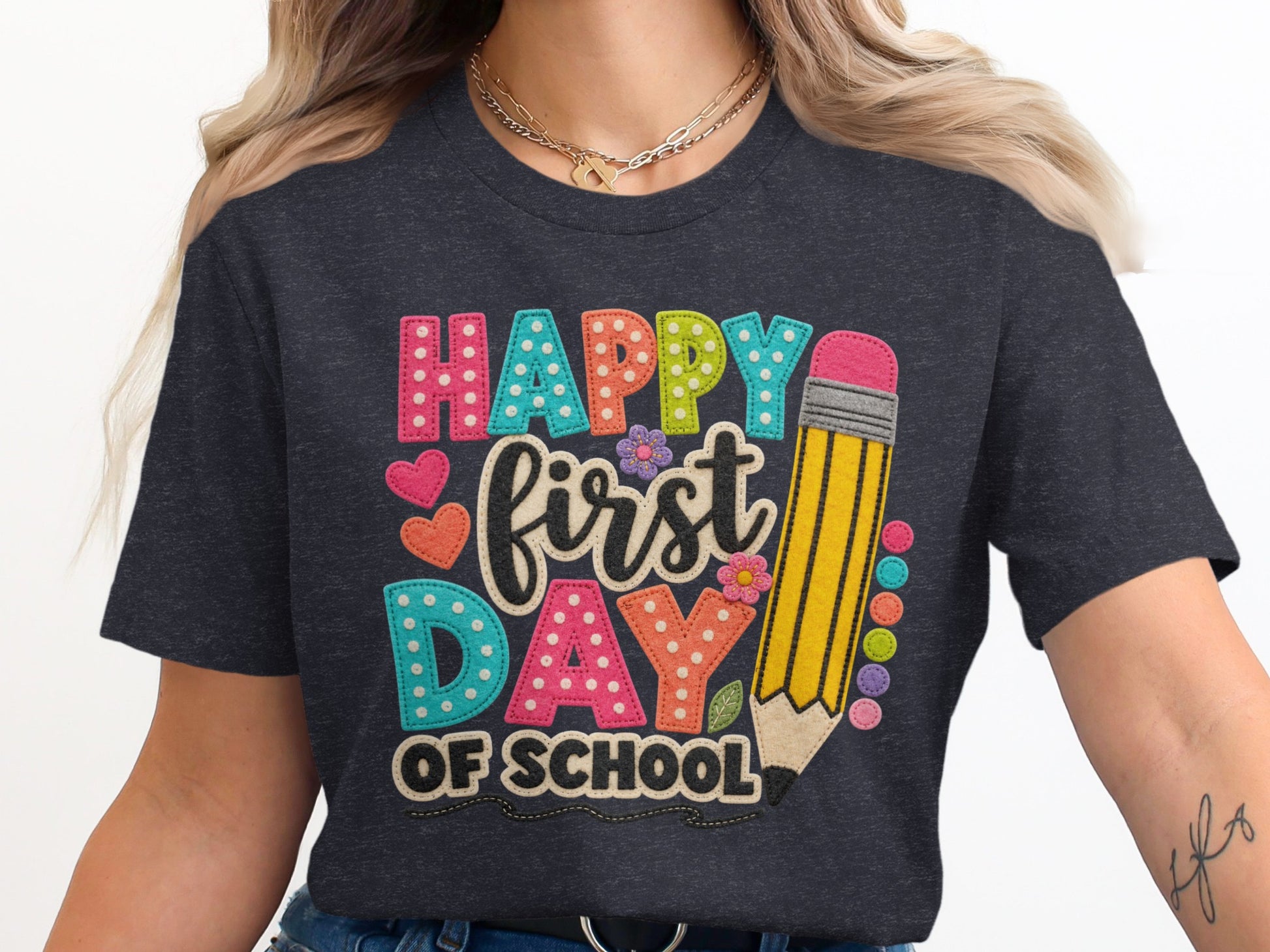 "Happy First Day of School" text with pencil and decorative elements on t-shirt.