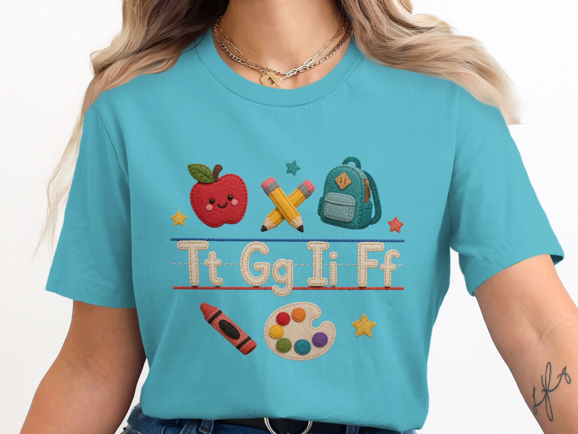T-shirt with embroidered apple, pencils, backpack, crayon, and letters Tt Gg Ii Ff.
