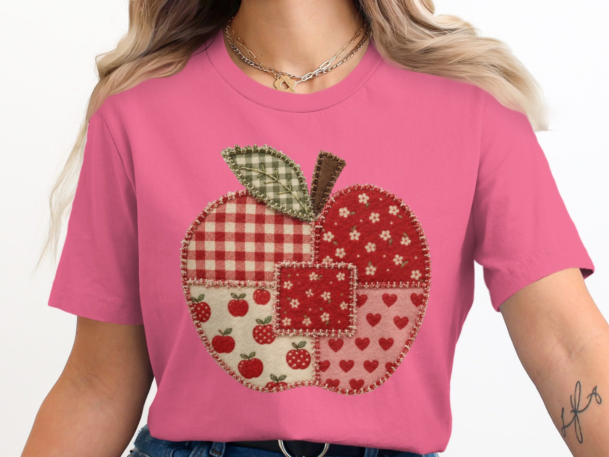 Pink t-shirt with a patchwork apple design featuring gingham, floral, apple, and heart patterns.