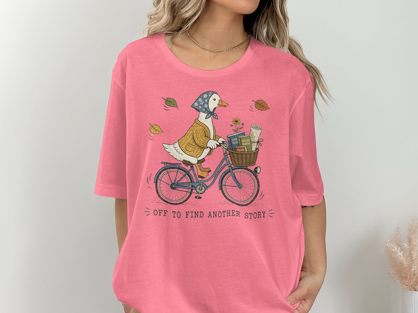 Duck riding bicycle with books in basket, "Off to find another story" text.