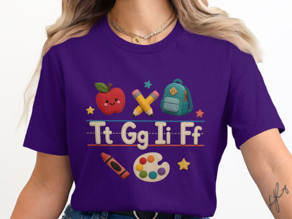 Purple t-shirt with embroidered alphabet letters, apple, backpack, pencils, crayon, and paint palette.