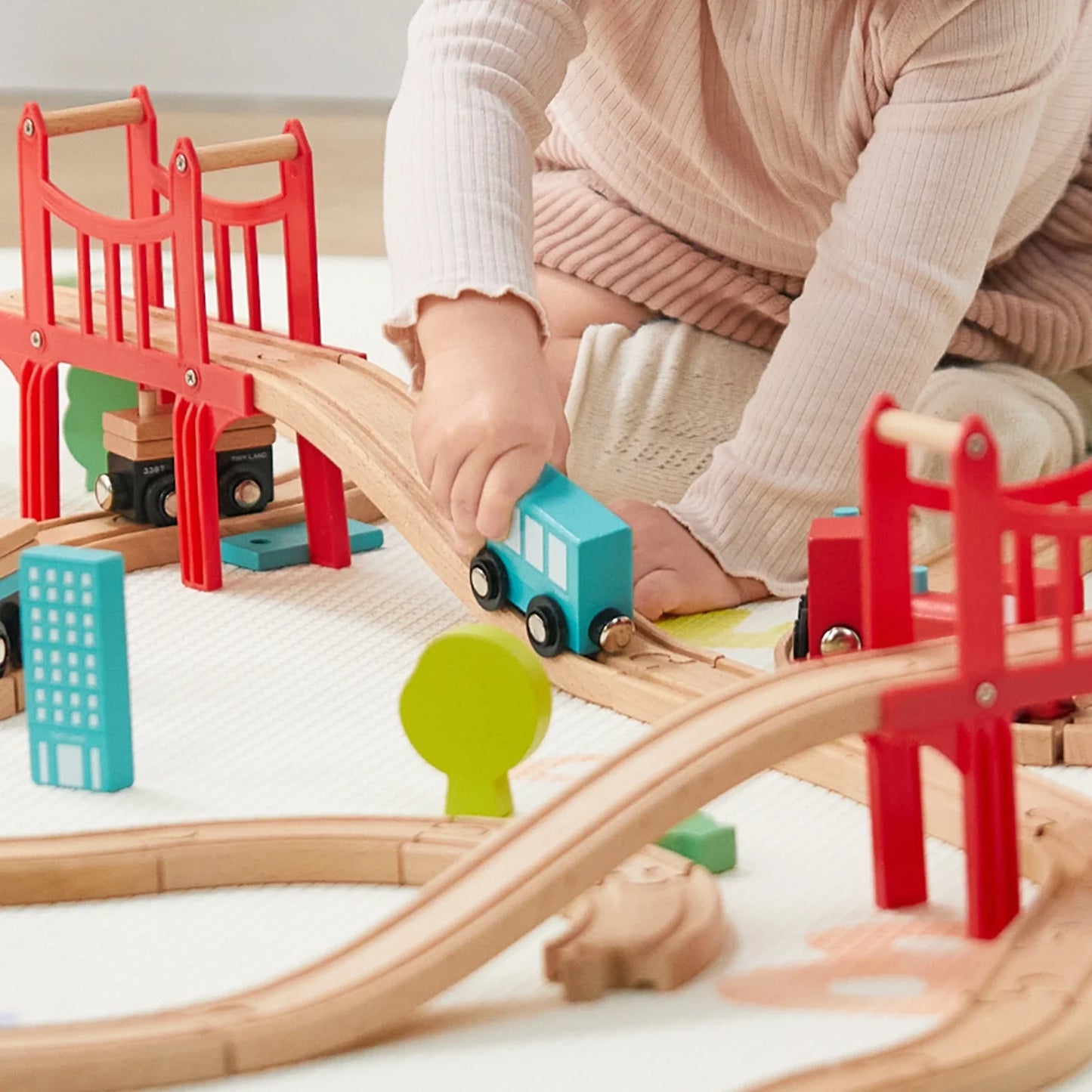 Preschooler playing with wooden train set on floor, building track layout Complete 39-piece wooden train set with tracks, toy trains, and accessories