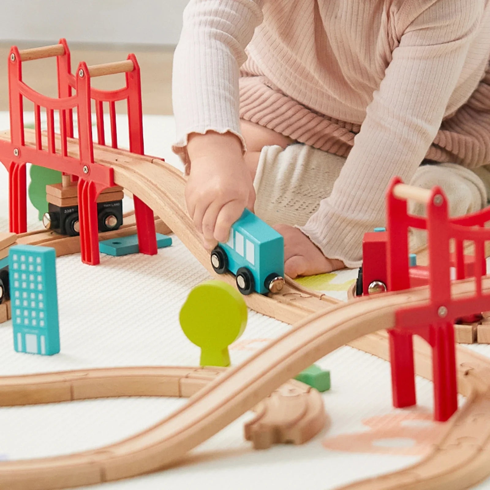 Preschooler playing with wooden train set on floor, building track layout Complete 39-piece wooden train set with tracks, toy trains, and accessories