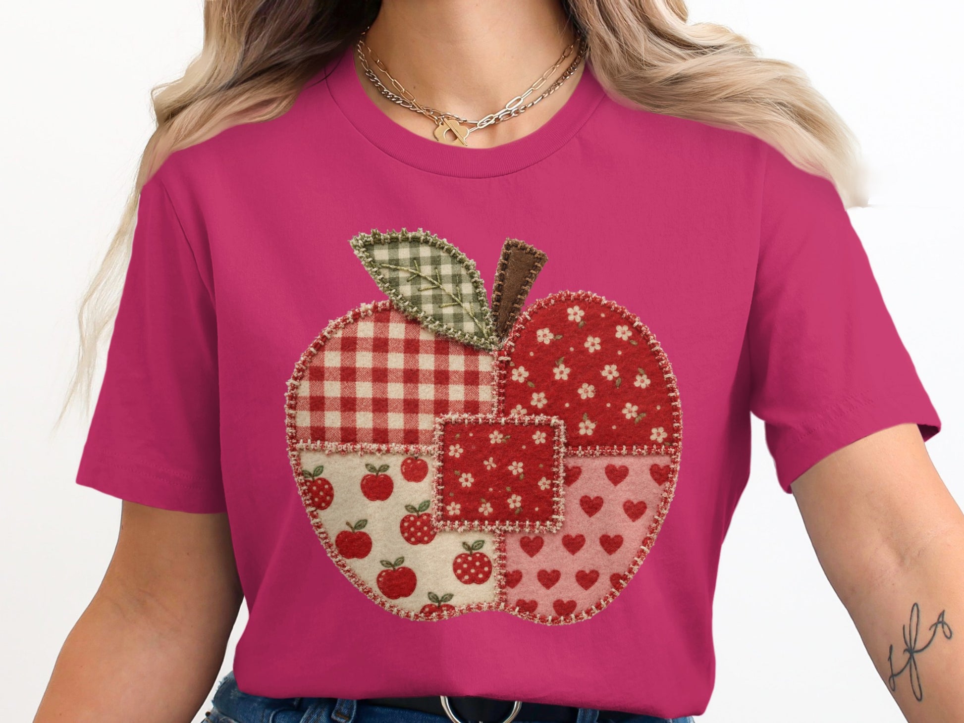 Pink t-shirt with a patchwork apple design featuring gingham, floral, and heart patterns.