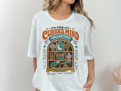 "The Curious Mind Collective" graphic tee with window display of nature and science items.