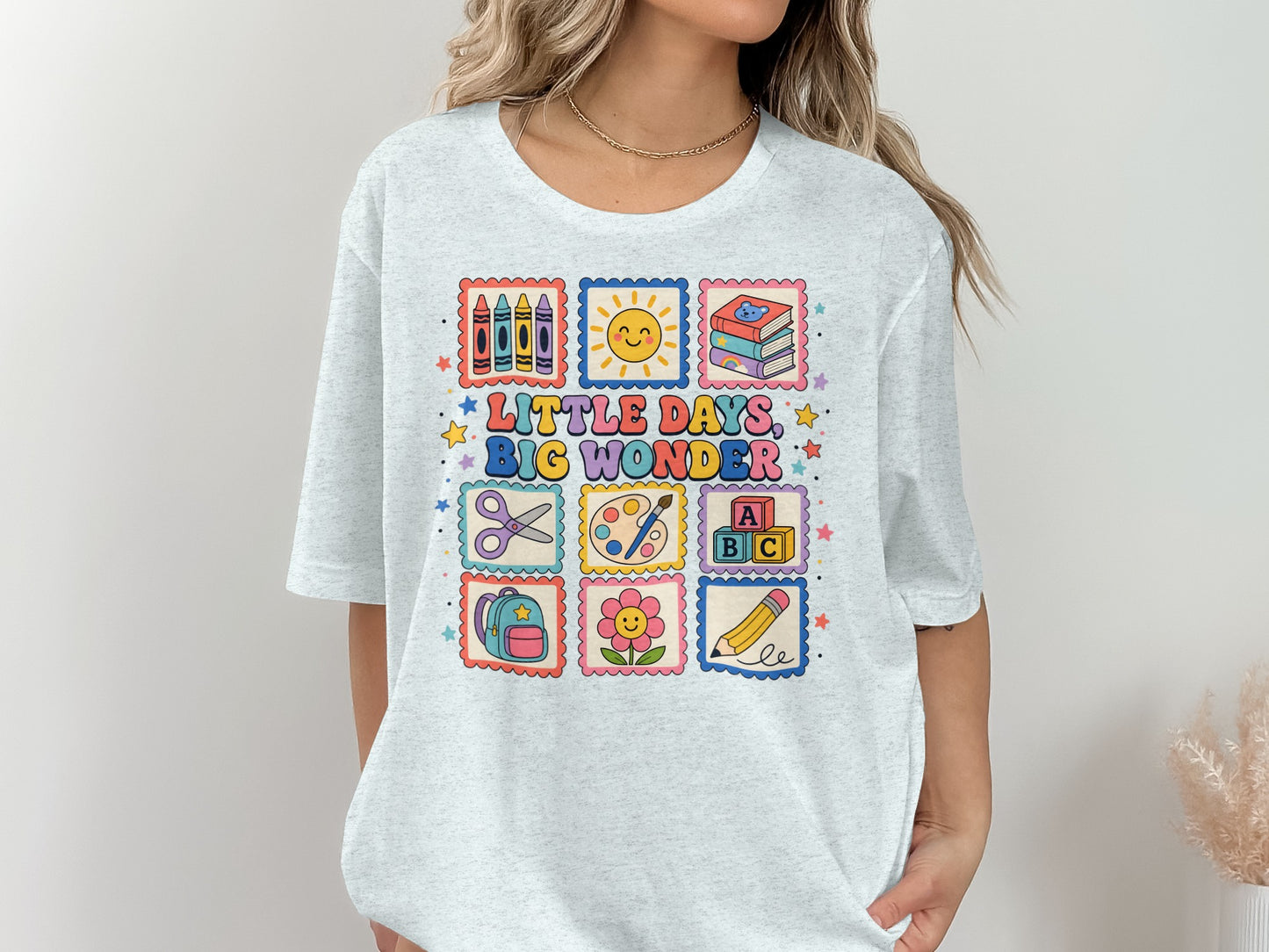 Light blue t-shirt with "Little Days, Big Wonder" and illustrated school supplies.