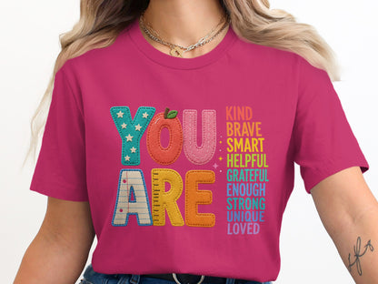 Pink t-shirt with "YOU ARE" and a list of positive adjectives.