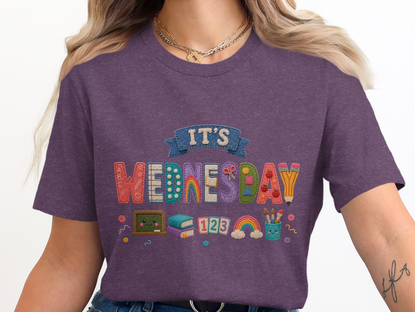 It's Wednesday text with school supplies, books, and rainbows on a purple shirt.