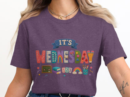 It's Wednesday text with school supplies, books, and rainbows on a purple shirt.
