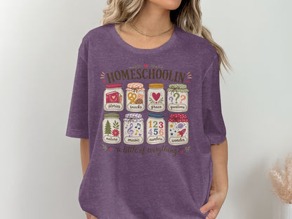 Homeschoolin graphic on purple t-shirt with jars of stories, snacks, grace, questions, nature, music, numbers, and wonder.