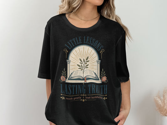 Black t-shirt with "Little Lessons Lasting Truth" text and an open book.