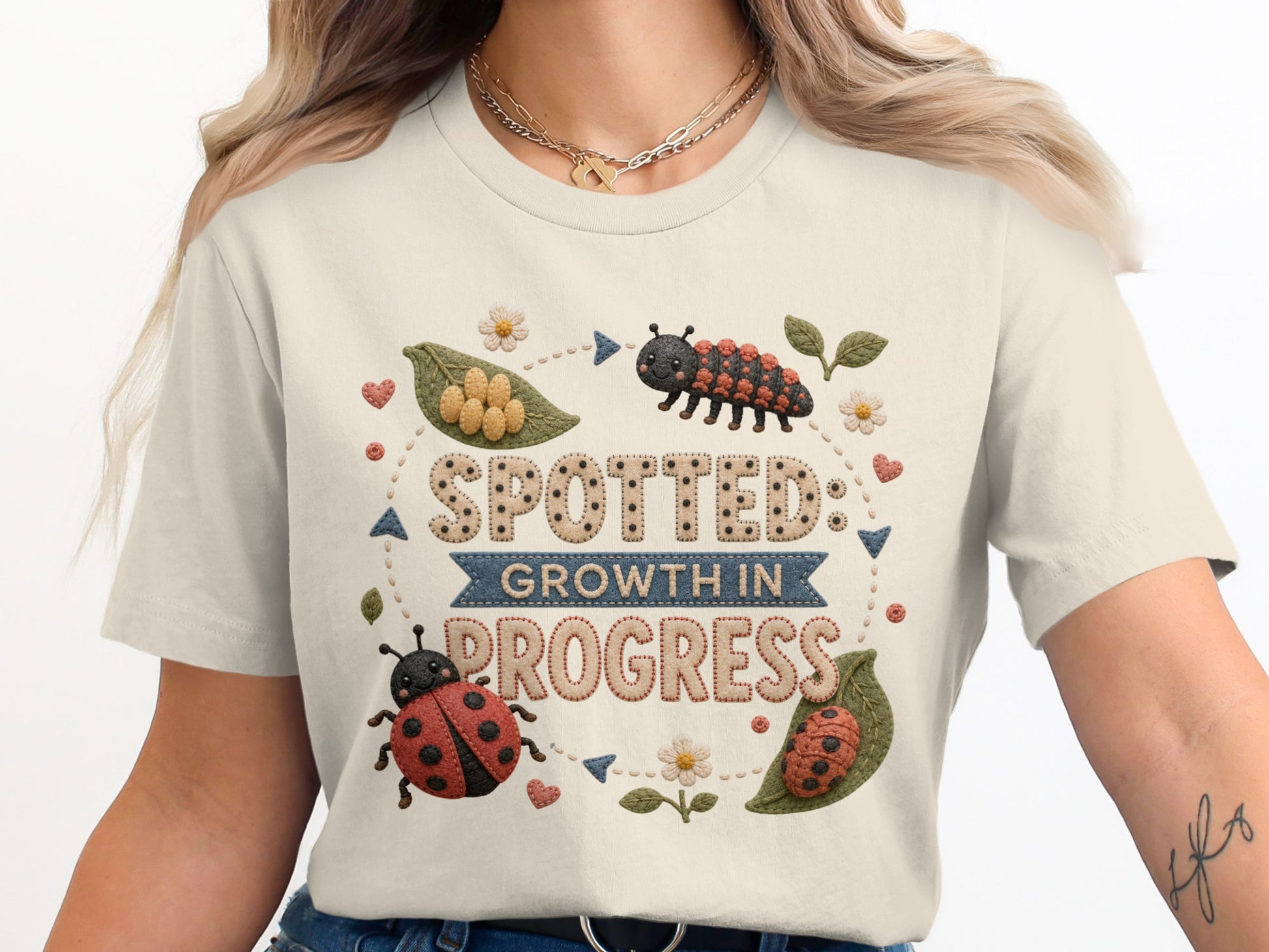 Cream t-shirt with "SPOTTED: GROWTH IN PROGRESS" text and ladybug illustrations.