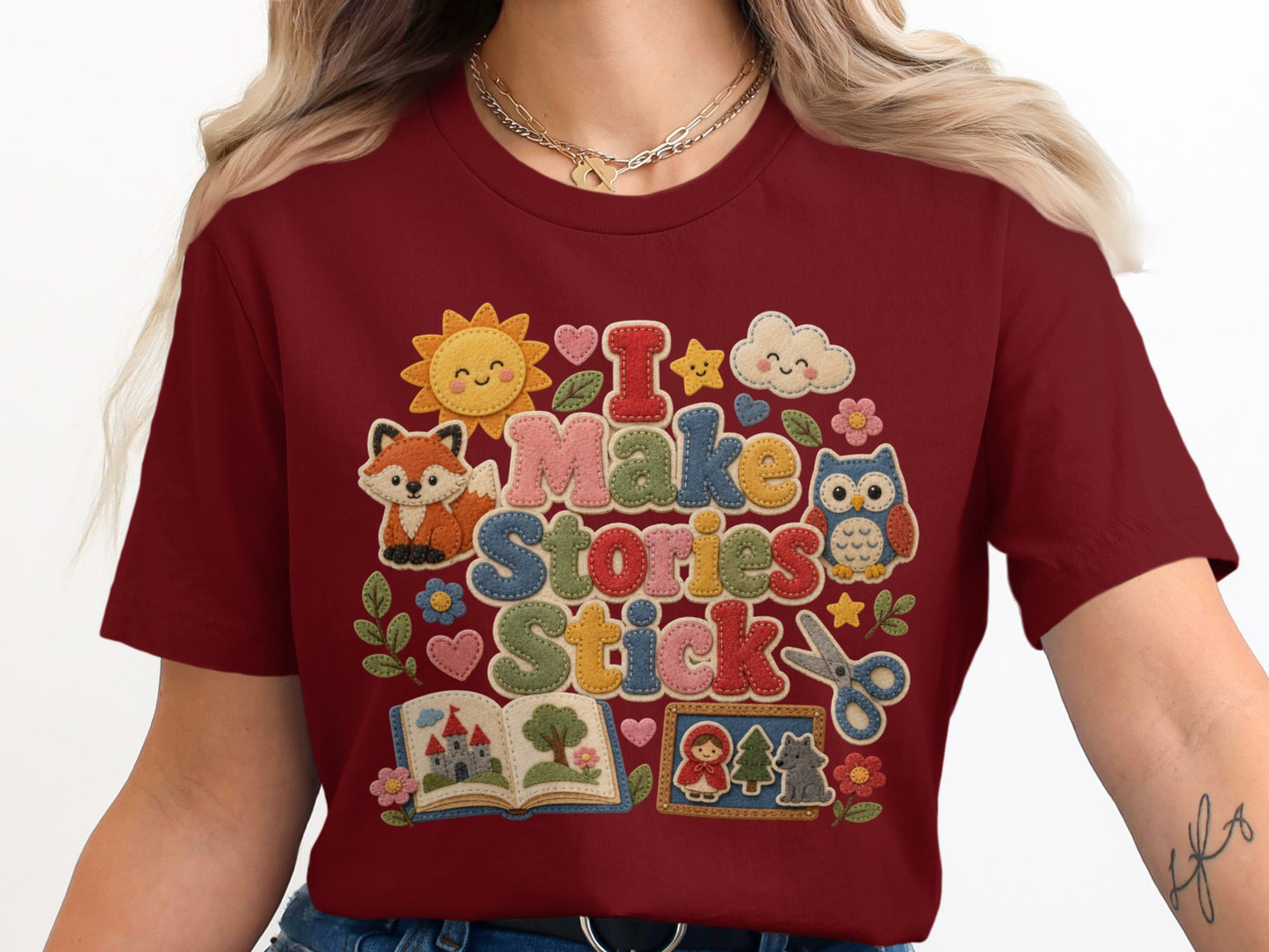 Maroon t-shirt with "I Make Stories Stick" text and classroom-themed felt appliques.