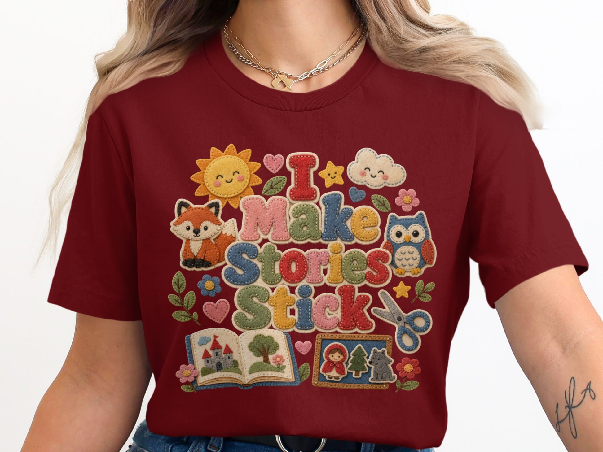 Maroon t-shirt with "I Make Stories Stick" text and classroom-themed felt appliques.