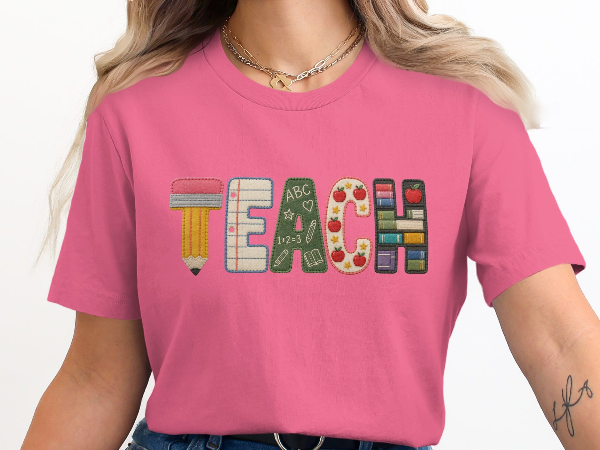 Pink t-shirt with "TEACH" embroidered in a playful alphabet of school supplies.