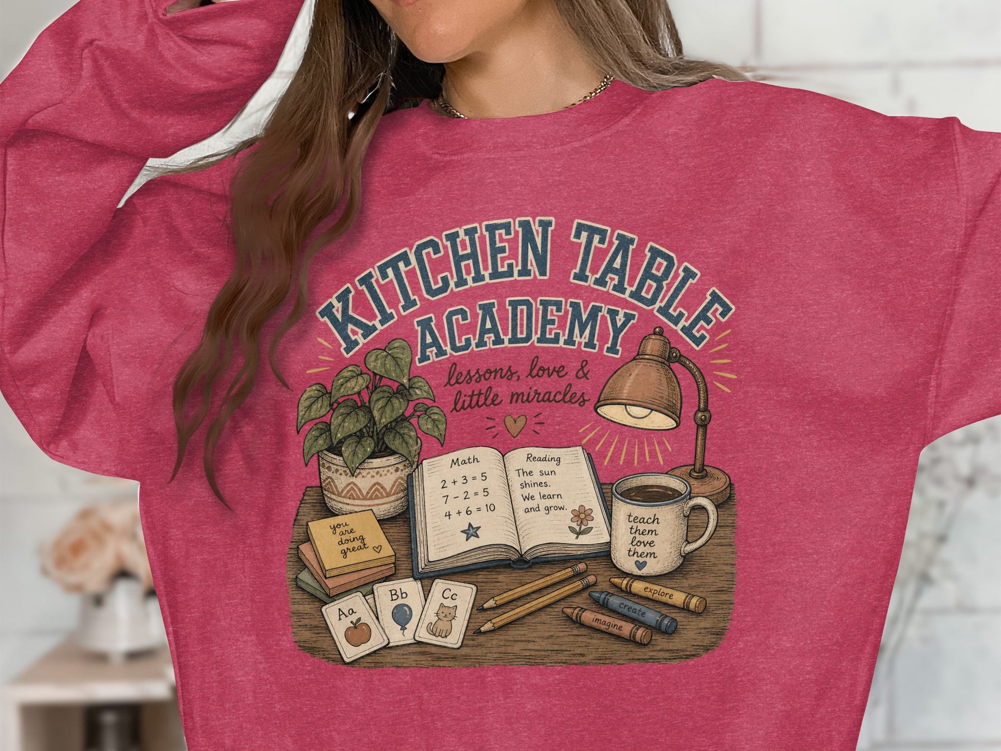 T-shirt graphic with "Kitchen Table Academy" and school-themed illustration.