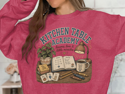 T-shirt graphic with "Kitchen Table Academy" and school-themed illustration.
