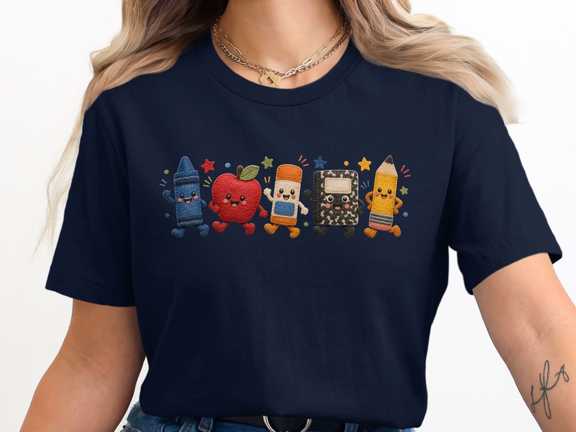 Navy tee with embroidered cartoon school supplies: crayon, apple, eraser, notebook, and pencil.