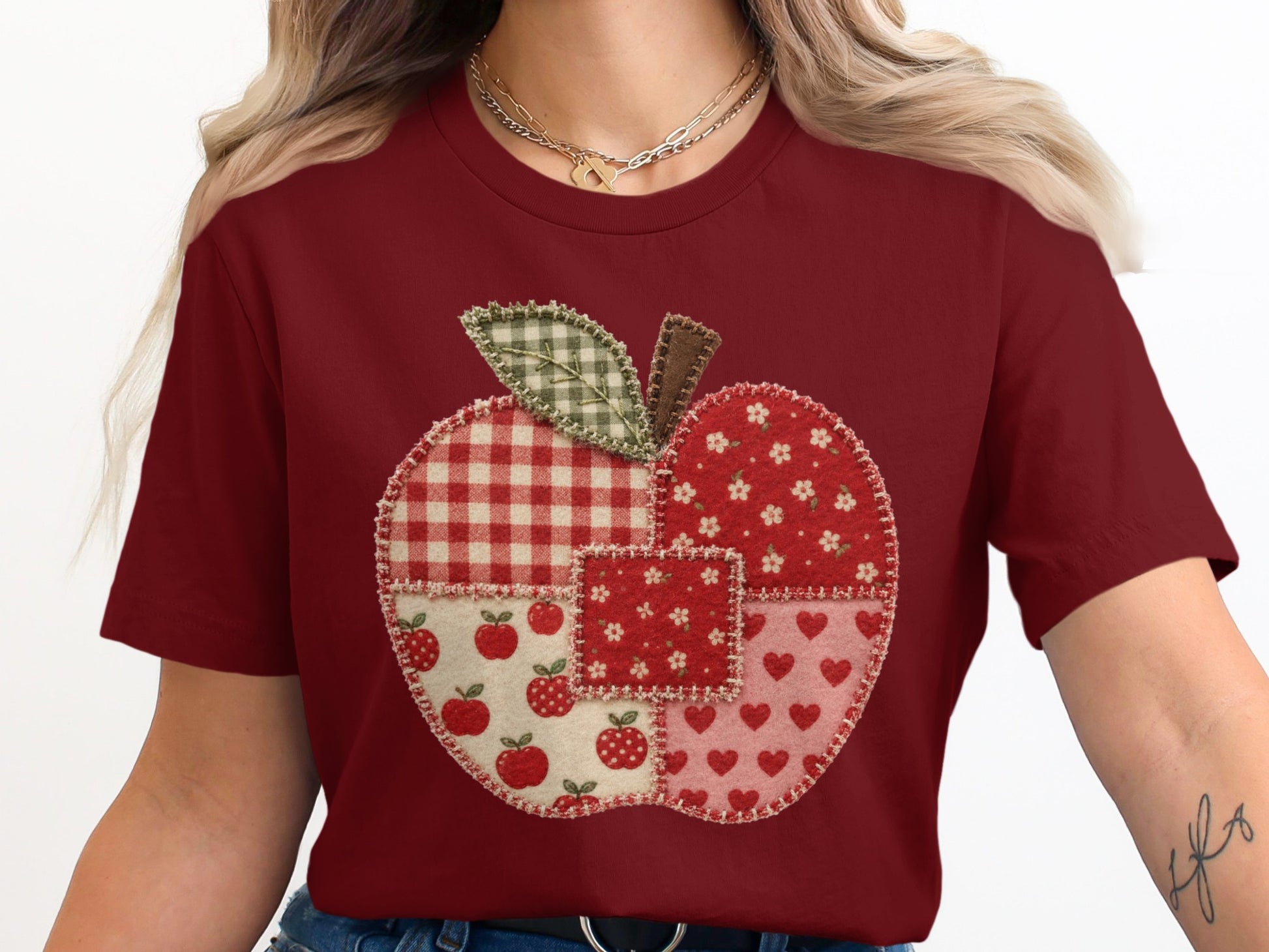Maroon t-shirt with a patchwork apple graphic featuring gingham, flowers, apples, and hearts.