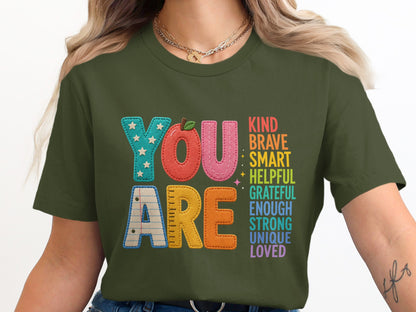 Green t-shirt with "YOU ARE" and positive affirmations in colorful block letters.
