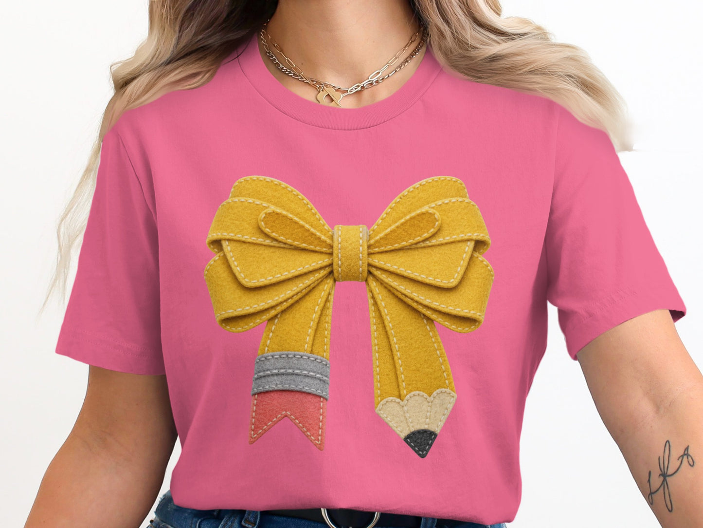 Pink t-shirt with a yellow pencil bow graphic and gold necklaces.