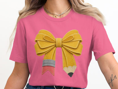 Pink t-shirt with a yellow pencil bow graphic and gold necklaces.