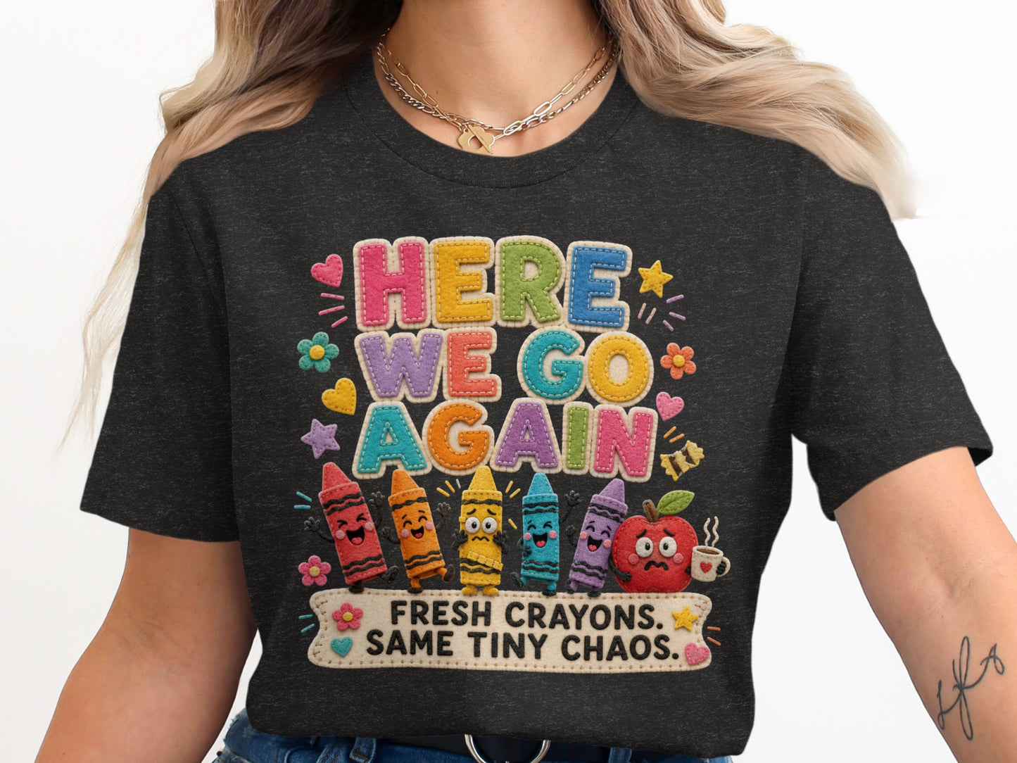 Dark gray t-shirt with "HERE WE GO AGAIN" and "FRESH CRAYONS. SAME TINY CHAOS." text.