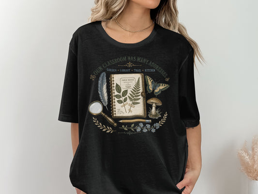 Black t-shirt with vintage botanical illustration and text "Our Classroom Has Many Addresses".