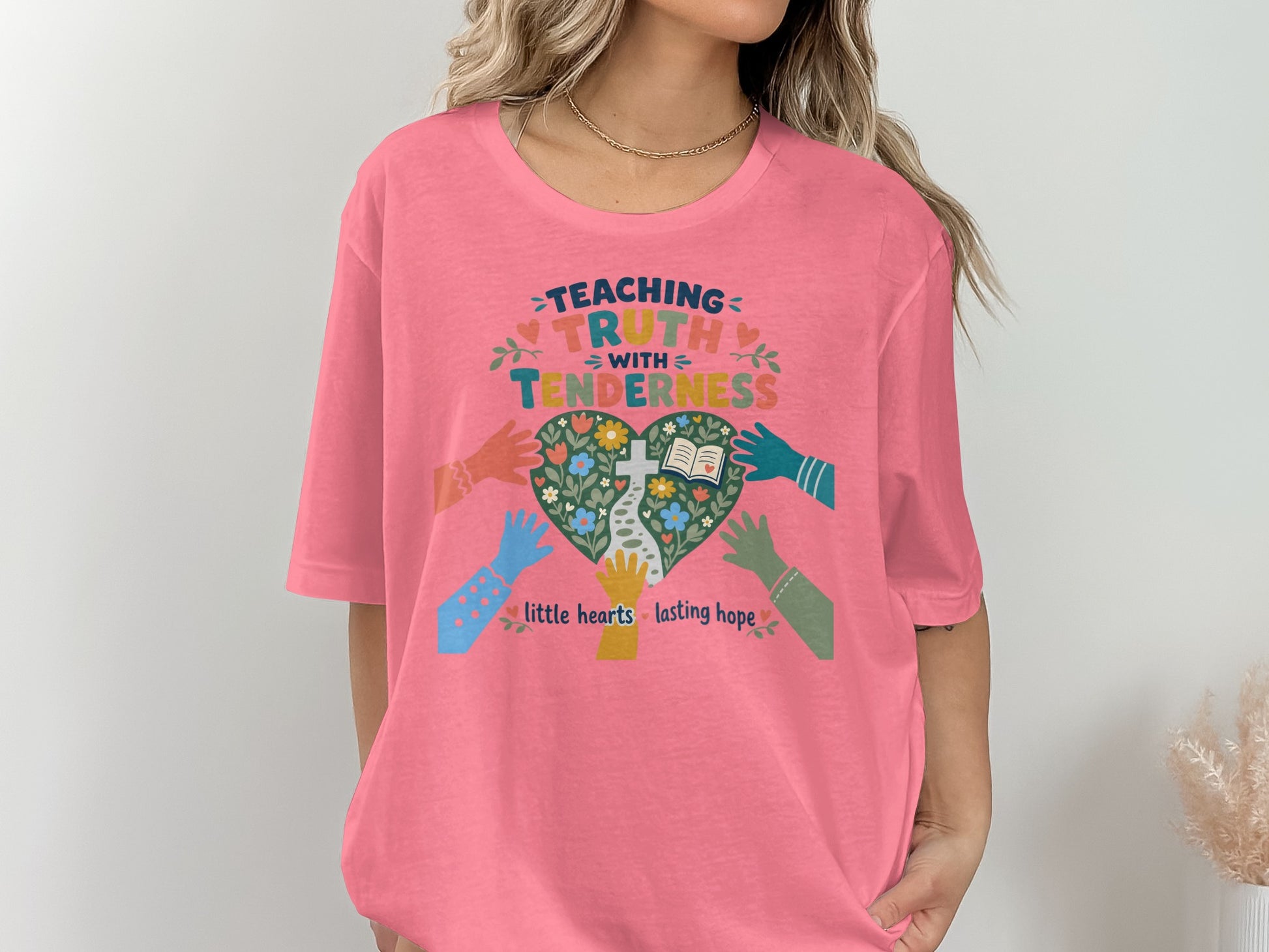 Teaachinf truth with tenderness, little hearts lasting hope graphic on a pink t-shirt.