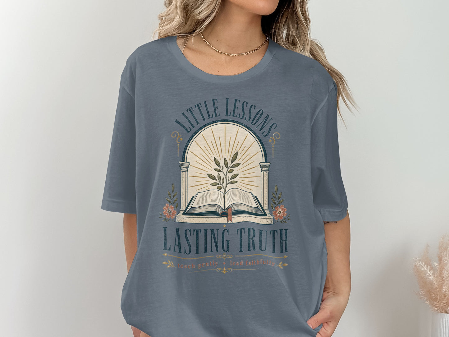 "Little Lessons Lasting Truth" graphic tee with an open book, plant, and flowers.
