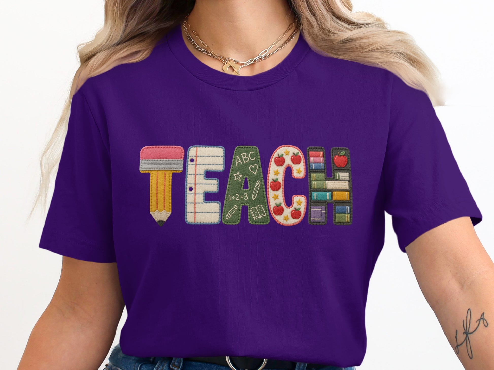 Purple t-shirt with embroidered "TEACH" design featuring school-themed letters.