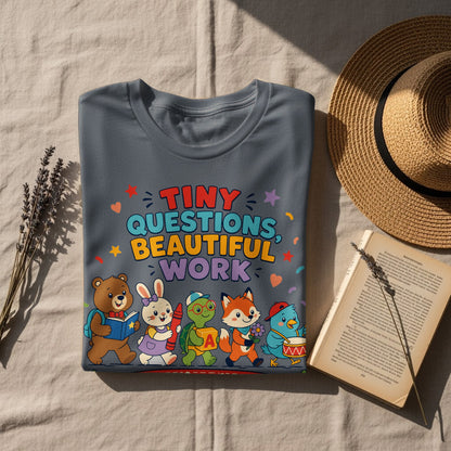 Gray t-shirt with cartoon animals and text "Tiny Questions, Beautiful Work."