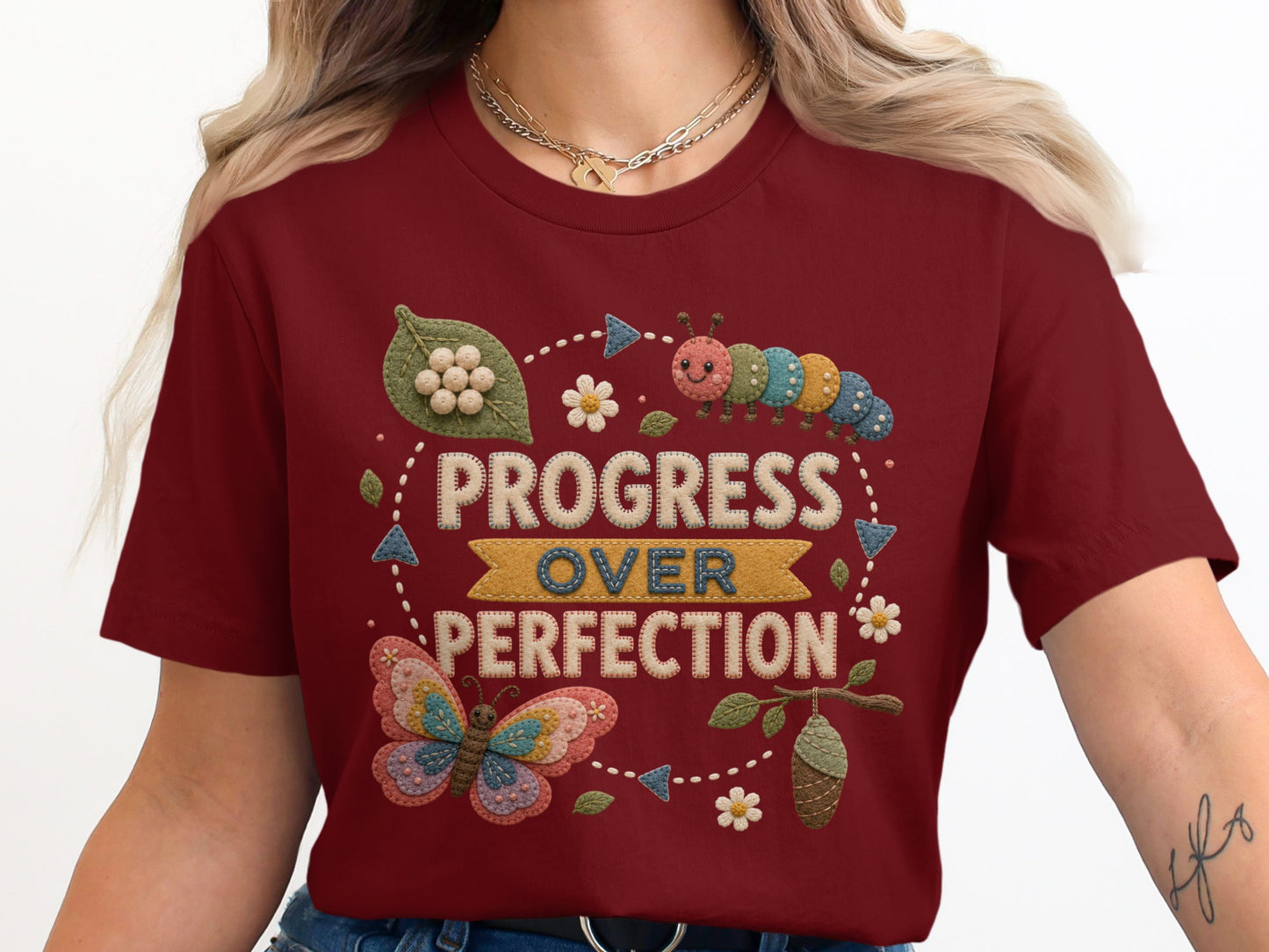 Burgundy t-shirt with "Progress Over Perfection" text and butterfly, caterpillar, and chrysalis graphics.