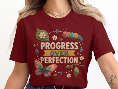 Burgundy t-shirt with "Progress Over Perfection" text and butterfly, caterpillar, and chrysalis graphics.