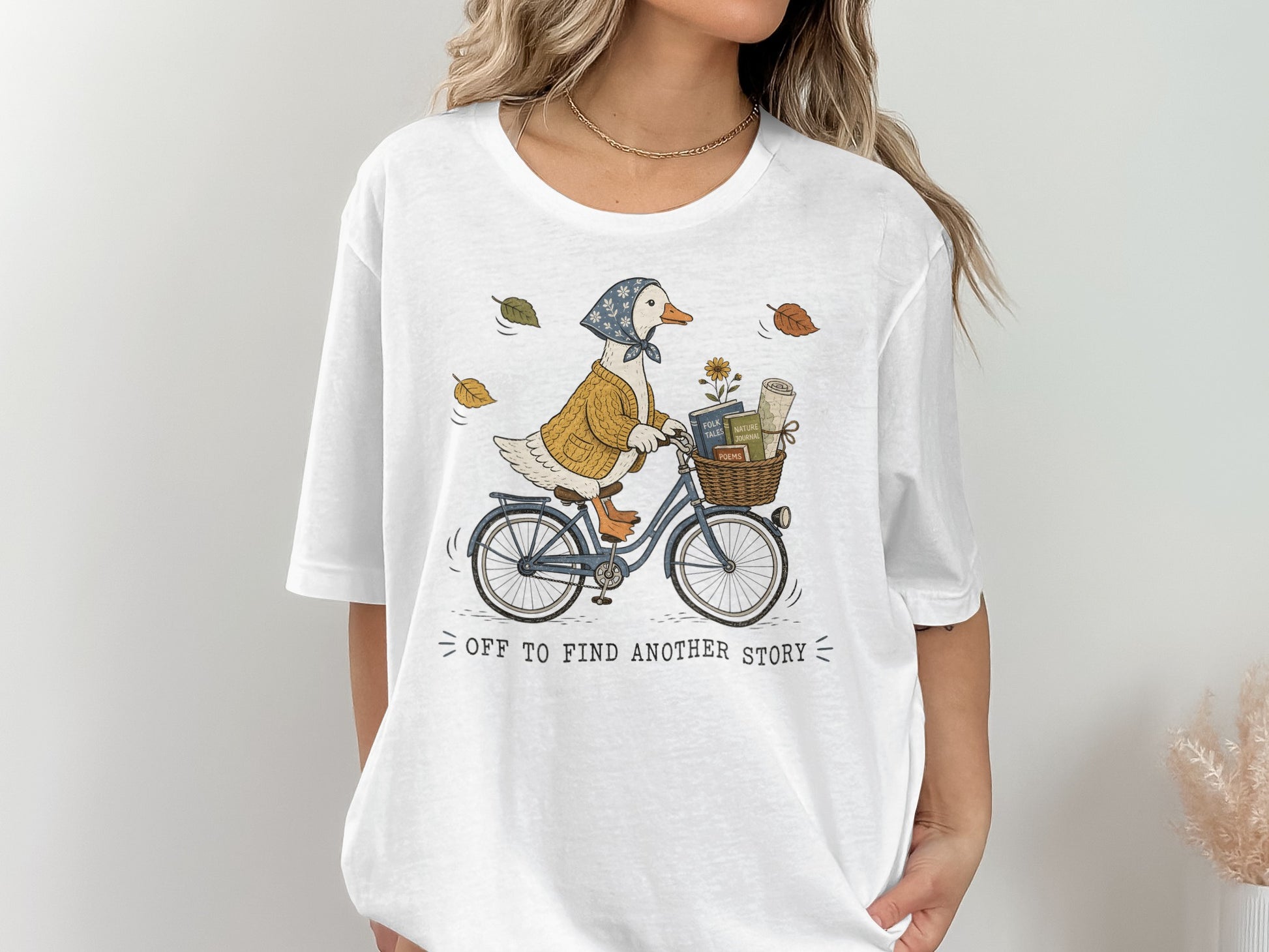 Duck on bicycle with books in basket, text "off to find another story".