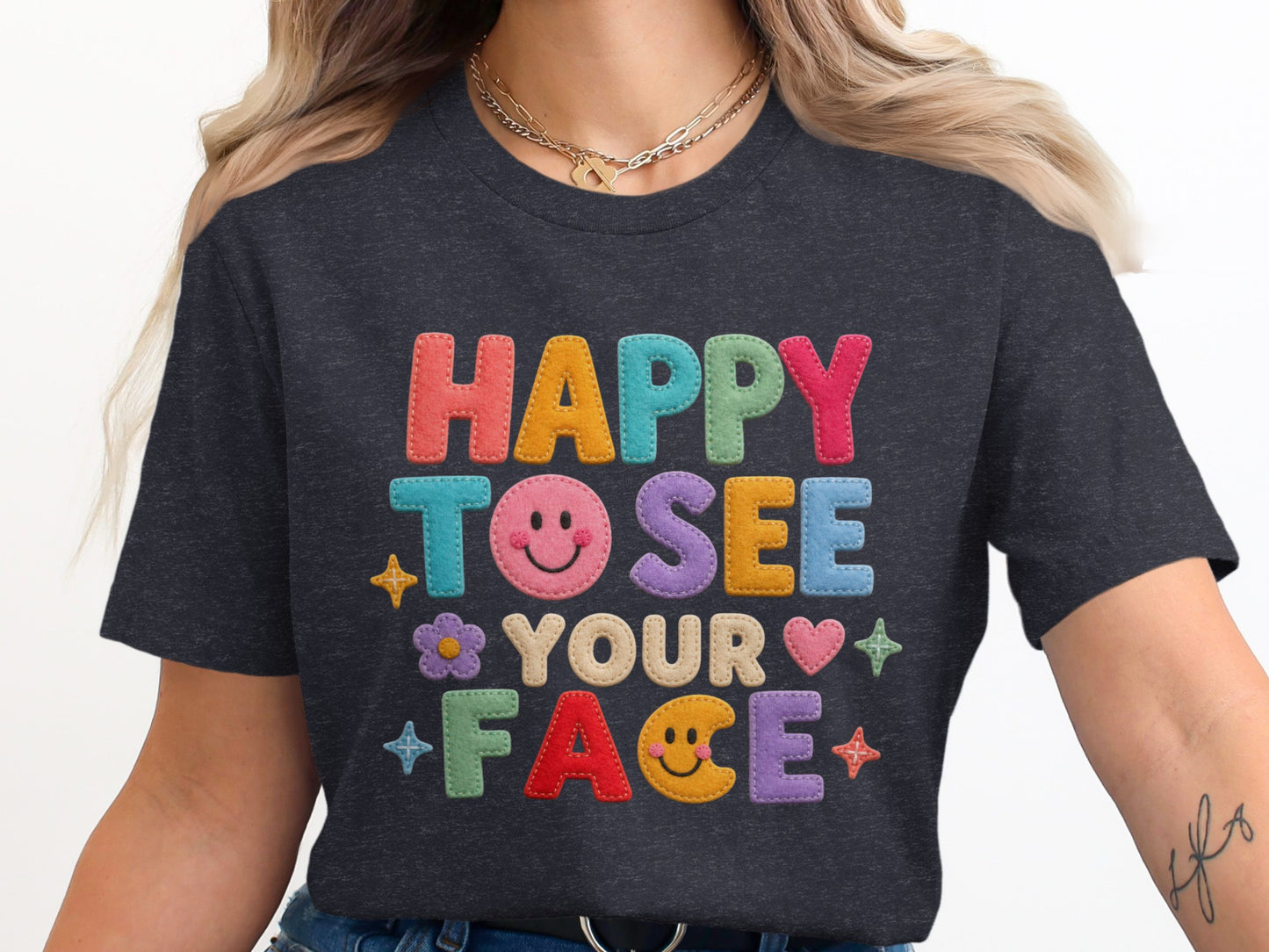 Dark grey t-shirt with "HAPPY TO SEE YOUR FACE" in colorful embroidered letters.