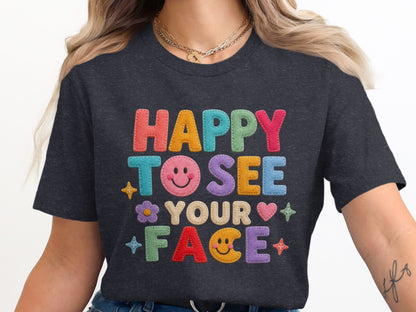 Dark grey t-shirt with "HAPPY TO SEE YOUR FACE" in colorful embroidered letters.