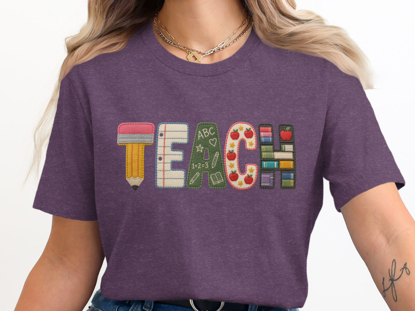Purple t-shirt with "TEACH" spelled out with school-themed embroidered letters.
